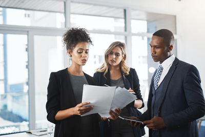 three business professionals discussing documents in a modern office setting highlighting teamwork and collaboration
