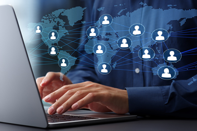 hands typing on laptop with digital world map and social network connections